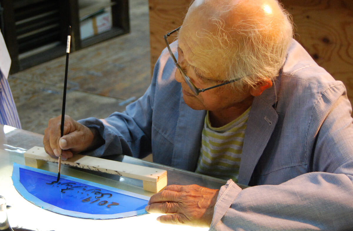 宮崎ブーゲンビリア空港ターミナルビル ステンドグラス 作品に使用するガラスにサインを入れる藤城氏