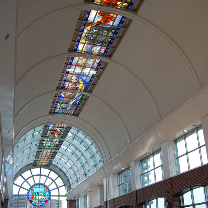 「筑後川」を背景に久留米の四季折々の自然や名所、祭事、名産品などをデザインしたステンドグラス（東口方向）