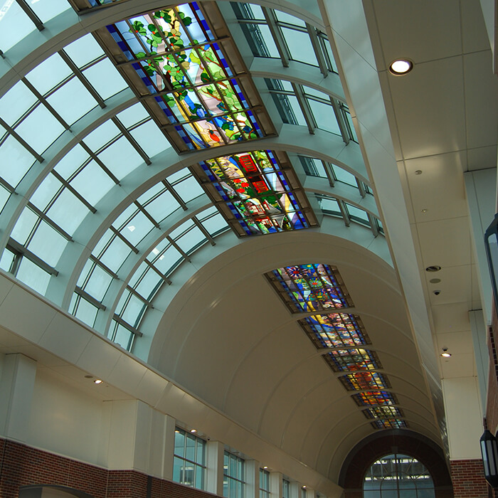 「筑後川」を背景に久留米の四季折々の自然や名所、祭事、名産品などをデザインしたステンドグラス（西口方向）