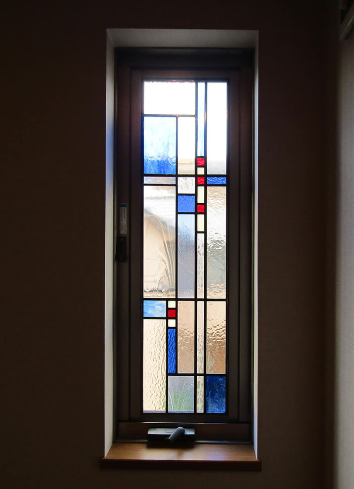 窓に取り付けたシンプルな幾何学デザインのステンドグラス（ブルー系）