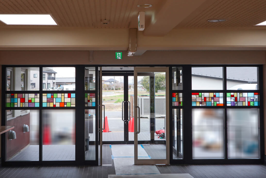施設のエントランスに取り付けた幾何学模様のデザインのステンドグラス