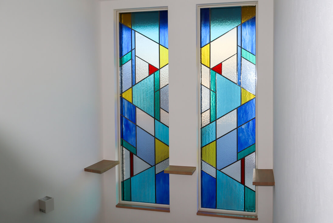 吹き抜けFIX窓に取り付けた、2枚組の幾何学模様デザインのステンドグラス（斜め）